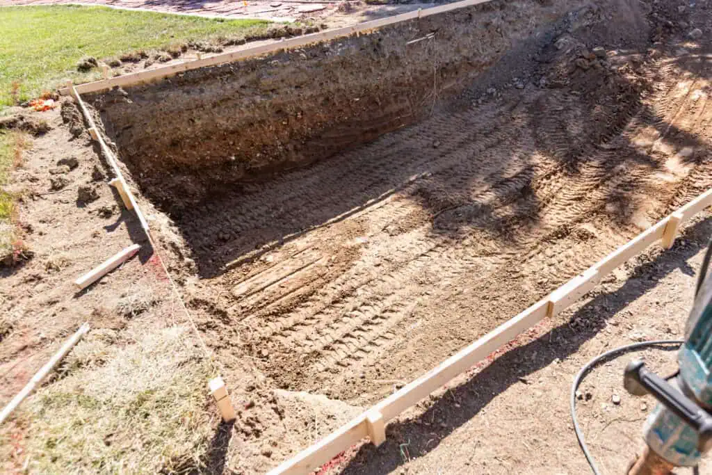 Excavated pool area ready for plastering at a construction site.