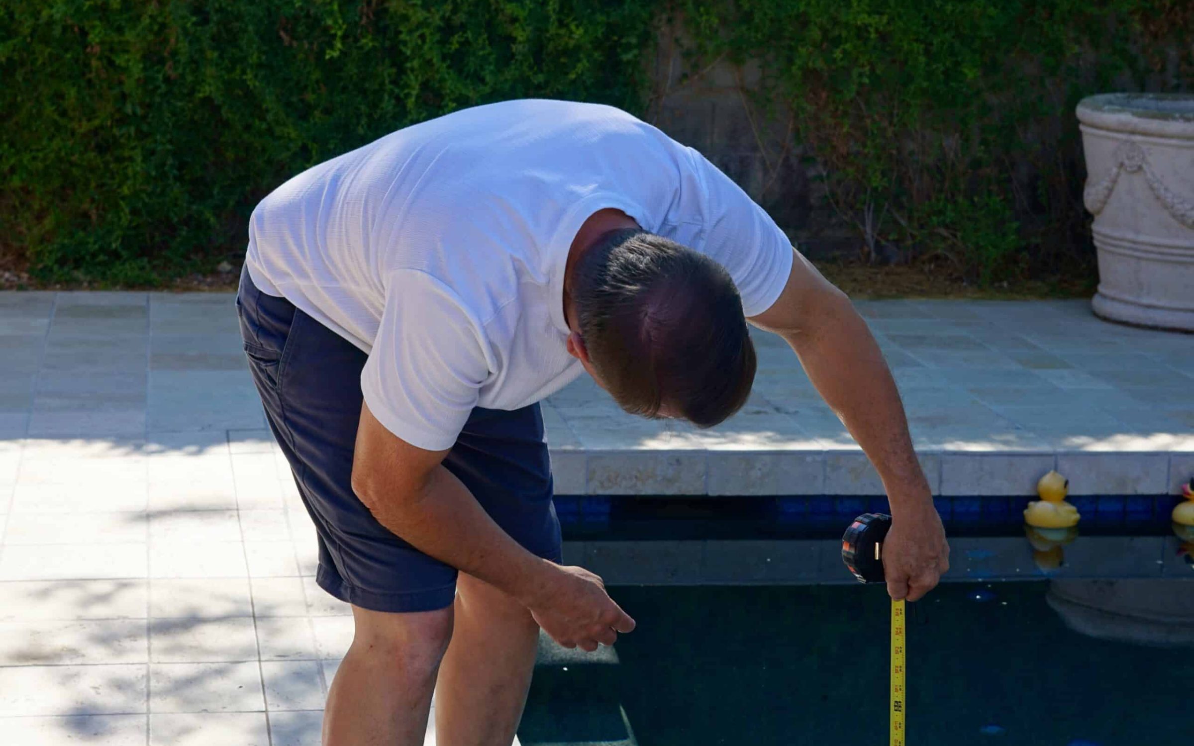 Pool plastering professional measuring pool surface for renovation.