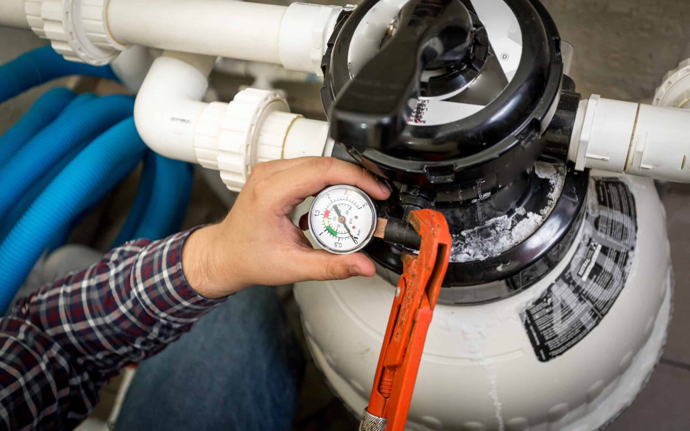 Technician inspecting pool pump and filtration system for optimal performance.