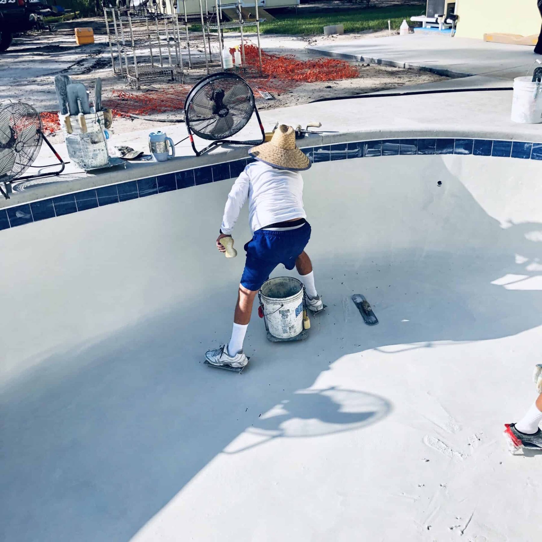 Child working on pool plastering during construction process.