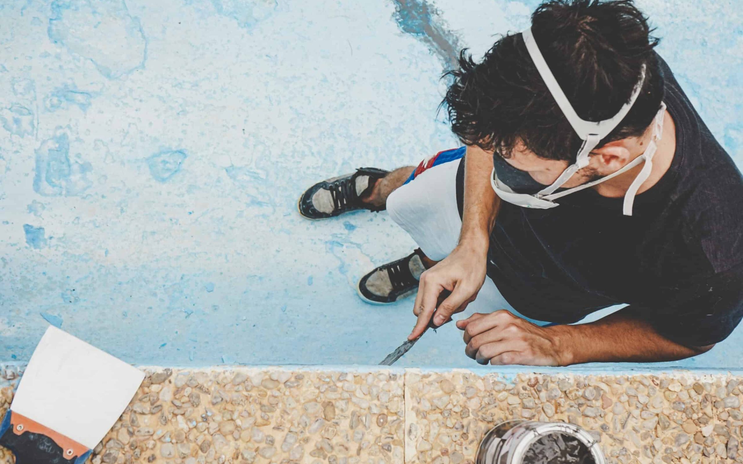 Pool plastering professional applying finishing coat in backyard pool.